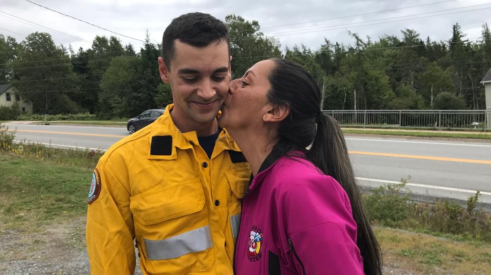 Shelley Falkenham plants a big kiss on the cheek of her son Gary. He's a newly minted firefighter who received his firefighting credentials in Nova Scotia and was off the next day to help fight the wildfires in British Columbia. In his community of ?? he's a hero. "I just love him," says Shelley. (Photo: Angel Moore/APTN)
